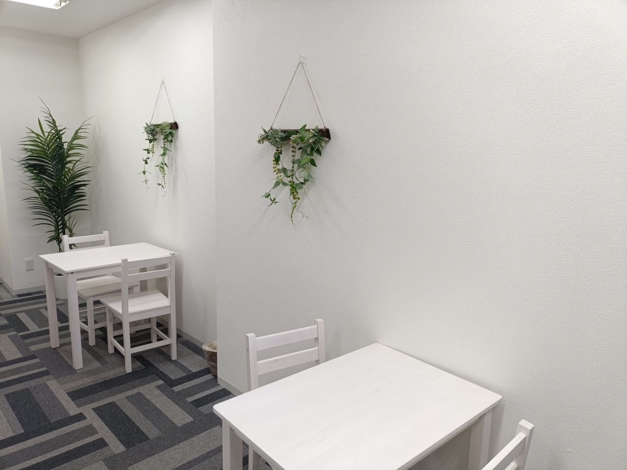 観葉植物が飾られた明るい個別学習スペース。白い机と椅子が並び、集中して取り組める環境